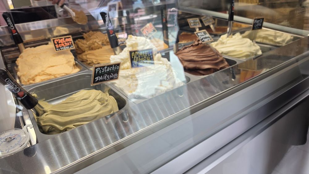 The gelato cabinet, tubs of pale swirled gelato lined up behind the glass.