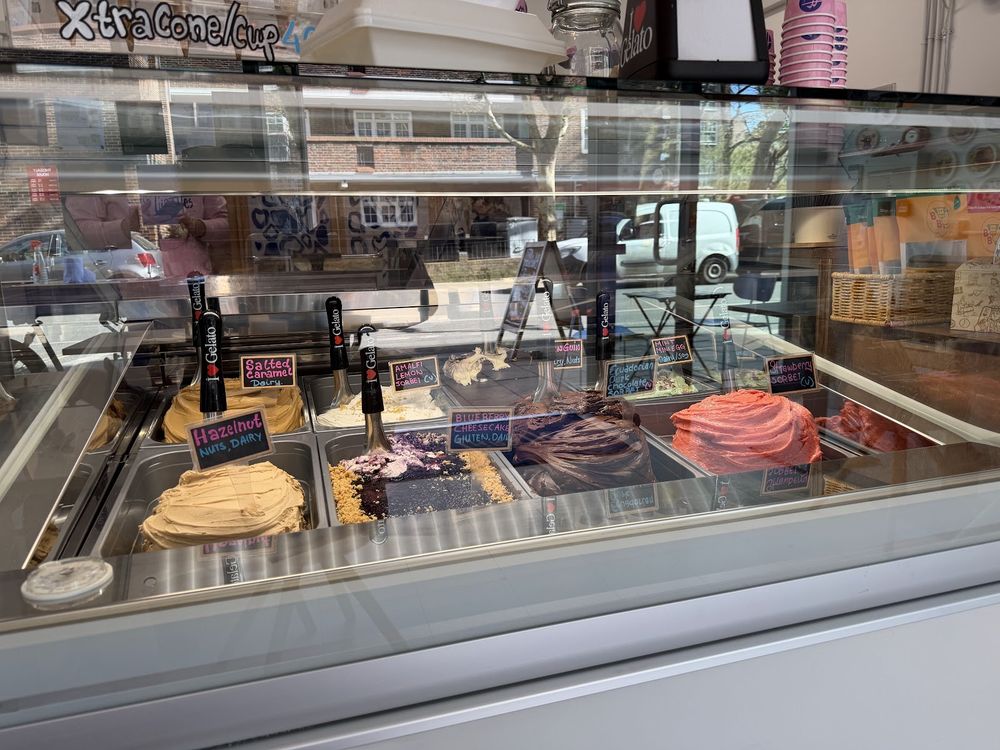 The long chilled counter of gelato and cakes with the coffee machine behind.